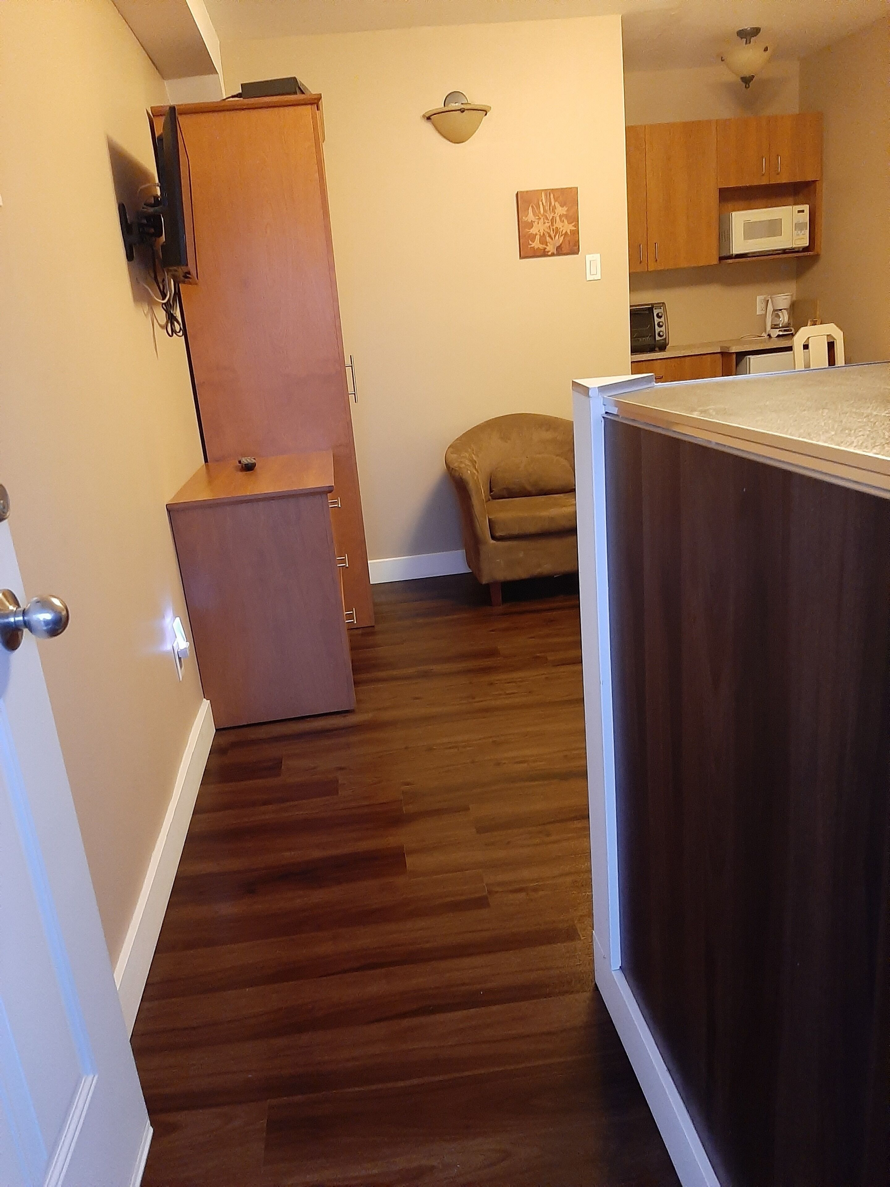 A compact kitchen with wooden cabinets, a microwave, and a small refrigerator.