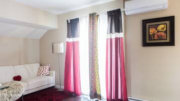 A living room with a white sofa, a red rug, and a patterned curtain.