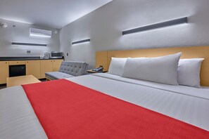 A hotel room with a large bed, a bedside table, a chair, a desk, a microwave, and a small kitchenette. - City Express by Marriott Hermosillo Expo (Hermosillo)