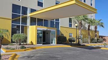 A modern building with a yellow facade, large windows, and a covered entrance.
