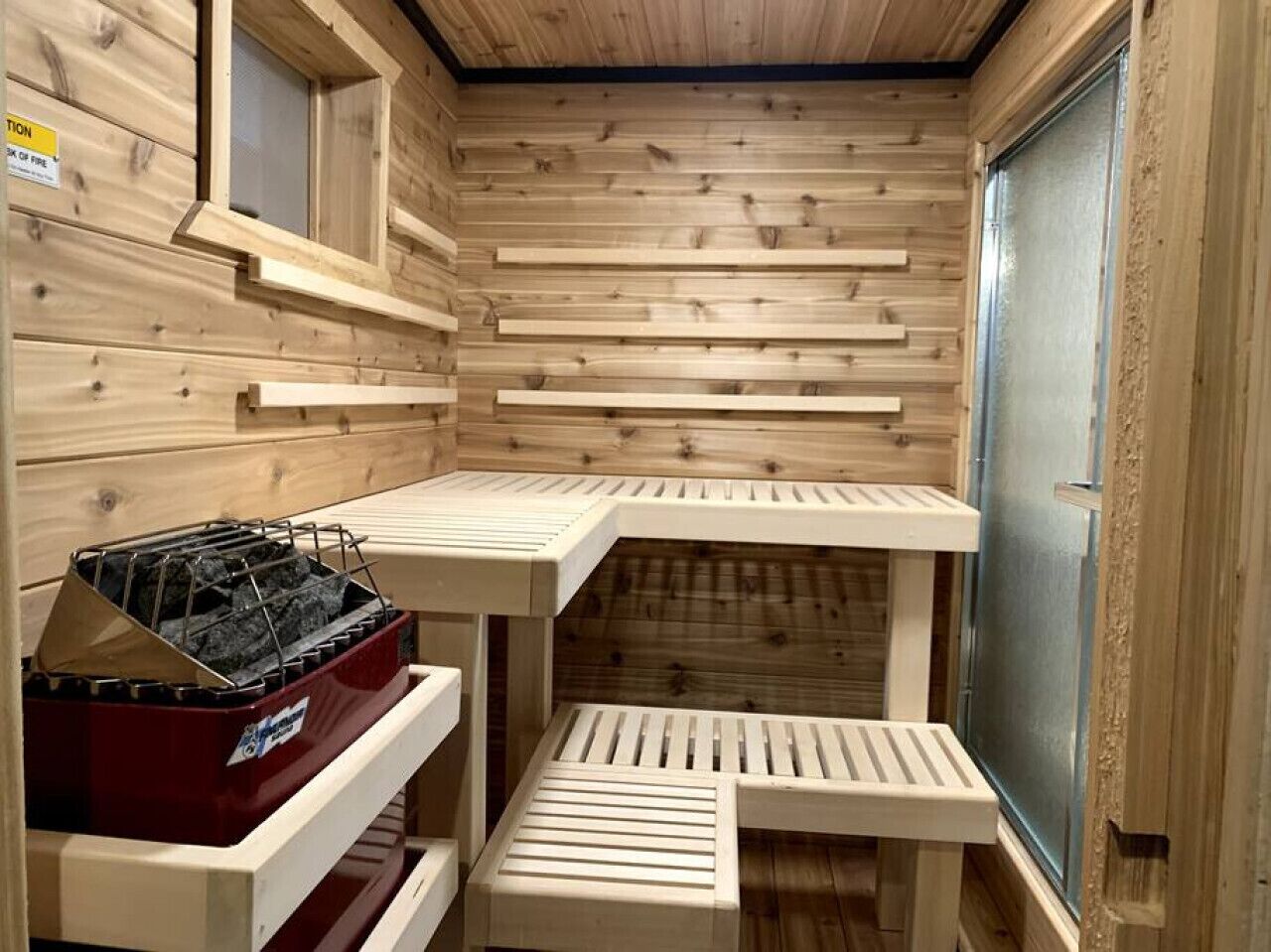 Un cuarto de sauna con paredes de madera, un banco y un baúl.