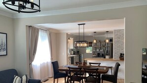 A modern living room with a dark blue sofa, a dining table with chairs, and a kitchen area in the background. - On the Trail-Cedar Sauna & Close to Ski & Trails (Ironwood)