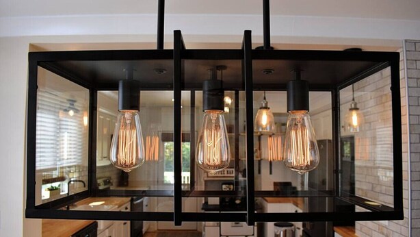 A modern kitchen with a central island, black pendant lighting, and a view of the adjacent dining area. - On the Trail-Cedar Sauna & Close to Ski & Trails (Ironwood)