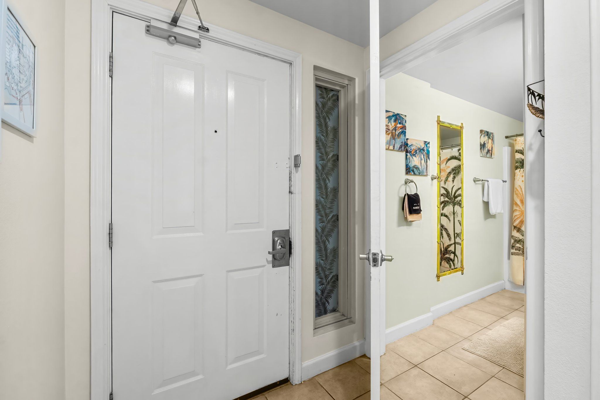 A hallway with a white door, a frosted glass door, and a tiled floor.
