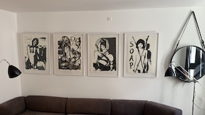A modern living room with a brown sectional sofa, a round black coffee table, and four black and white framed artworks on the wall. - Apartment 1 bedroom Grønnegade (Copenhagen)