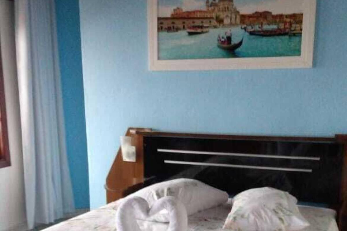 A neatly made bed with a floral bedspread and two towels arranged in a swan shape.