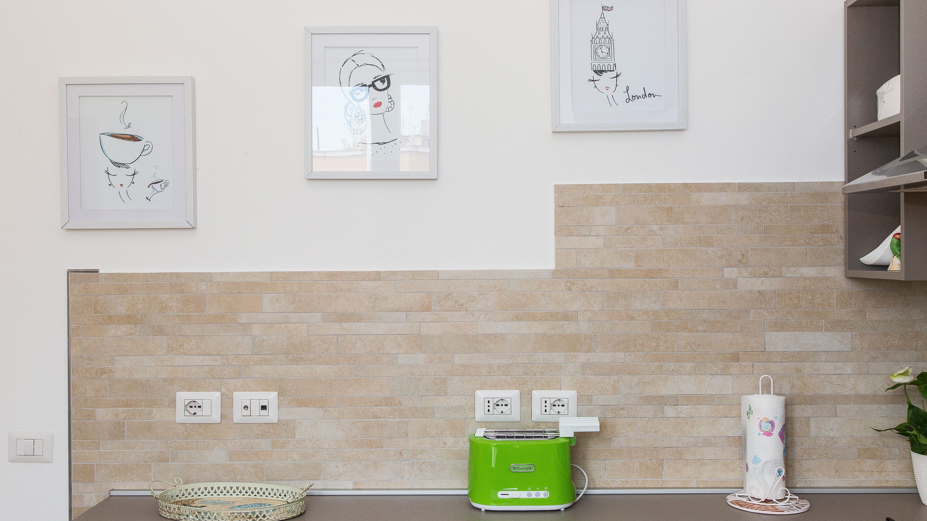 A kitchen with a brick backsplash, a green toaster, and a white candle holder.