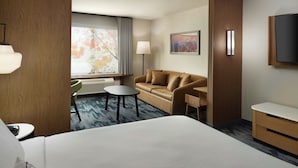 A hotel room with a large bed, a sofa, a small table, a desk, a TV, and a window with curtains. - Fairfield Inn & Suites by Marriott Locust Grove I-75 South (Locust Grove)