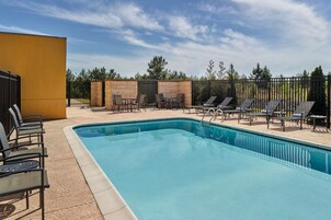 Una piscina rectangular con borde de azulejos, rodeada de sillones y mesas.