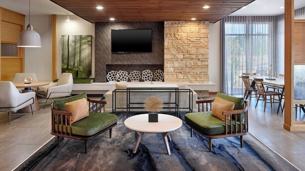 A modern living room with a fireplace, comfortable seating, and a flat-screen TV mounted on the wall. - Fairfield Inn & Suites by Marriott Locust Grove I-75 South (Locust Grove)