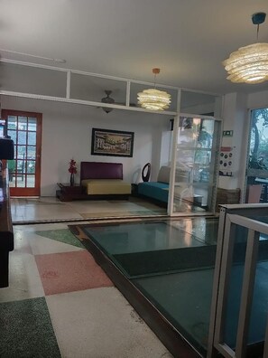 A room with a glass partition, a sofa, a ceiling fan, and a framed picture on the wall. - Hotel Boutique Bahia Plaza (Santa Marta)