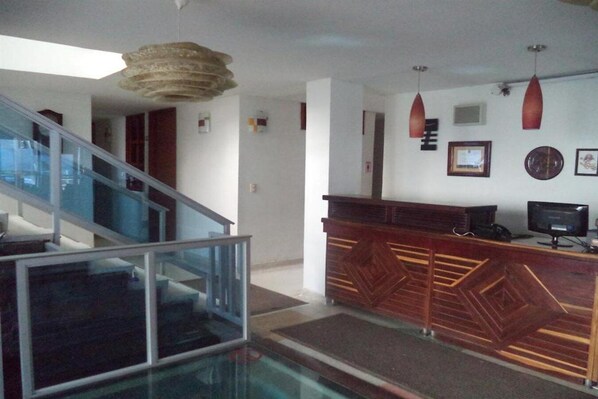A reception area with a wooden counter, a glass railing, and a staircase. - Hotel Boutique Bahia Plaza (Santa Marta)