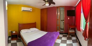 A bedroom with a bed, a ceiling fan, an air conditioning unit, a TV, and a checkered floor. - Hotel Boutique Bahia Plaza (Santa Marta)