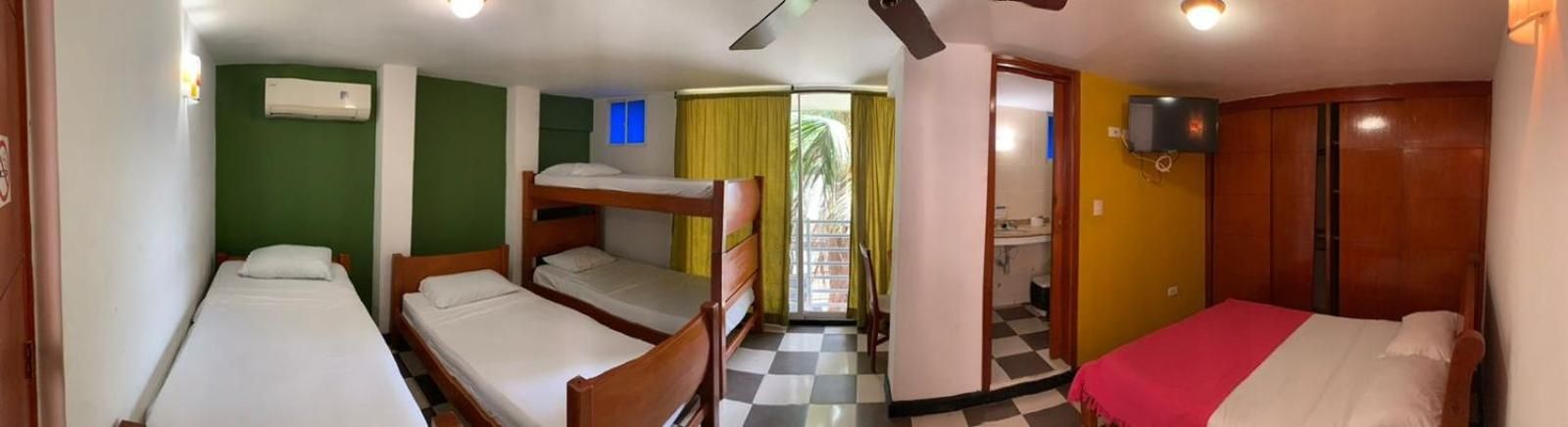 A room with bunk beds, a television, and a bathroom visible through an open door.