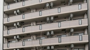 A multi-story building with balconies, air conditioning units, and a garage entrance. - Grand Court Namba 402 (Osaka)