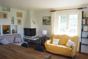 Ein Wohnzimmer mit Sofa, Fernseher, Kamin, Tisch und Bücherregal.