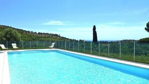 A rectangular swimming pool with clear blue water, surrounded by a glass railing. There are lounge chairs along the poolside. - Villa in Roquebrune with Sea View & Pool (Roquebrune-sur-Argens)