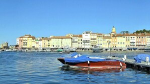 A waterfront with colorful buildings and boats docked at a pier. - Villa in Roquebrune with Sea View & Pool (Roquebrune-sur-Argens)
