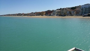 Un pueblo costero con edificios a lo largo de la playa, agua azul cristalina y un bote en primer plano.