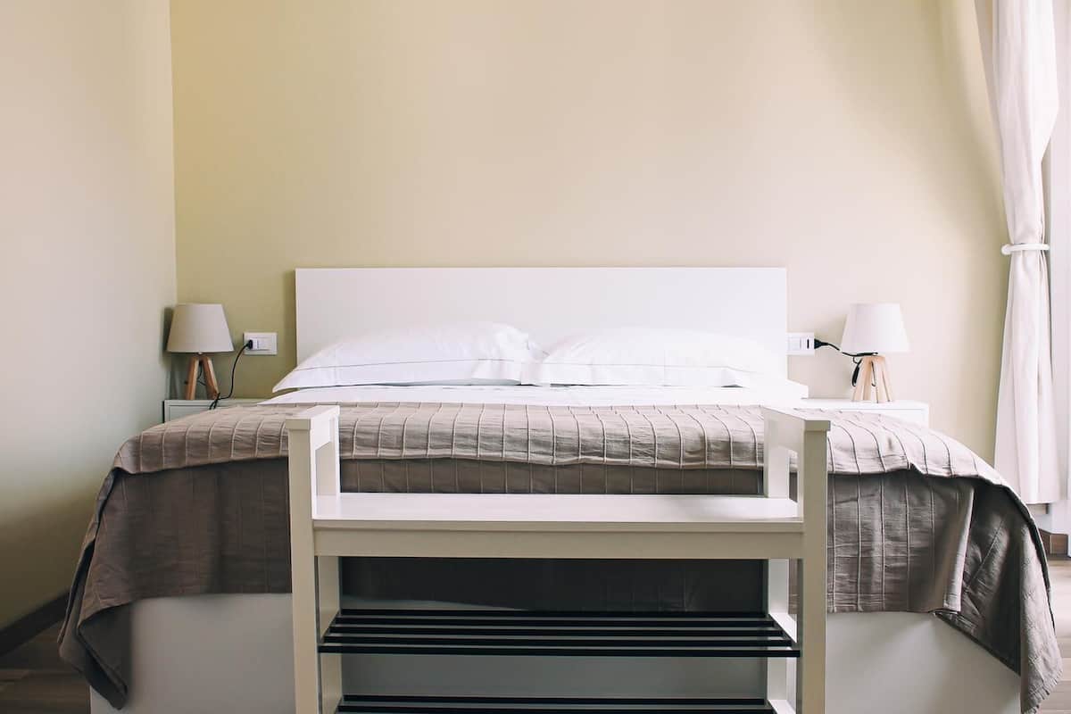 A neatly arranged bedroom with a bed, bedside lamps, and a small table.