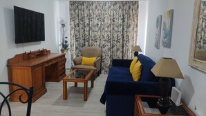 Ein Wohnzimmer mit einer Couch, einem Sessel, einem Holztisch und einem Fernseher.