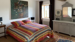 Een slaapkamer met een groot bed, een dressoir, een spiegel en een schilderij aan de muur.