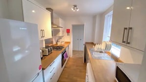 A modern kitchen with white cabinets, a built-in oven, a microwave, and a gas stove.