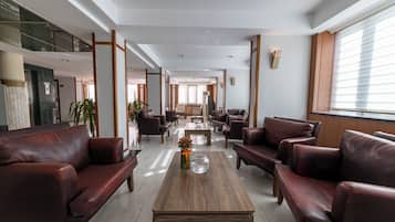 Un vestíbulo amplio con sofás de cuero, una mesa de centro de madera y un gran ventanal.