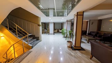 Un interior moderno con una escalera, una zona de estar y un techo de cristal.