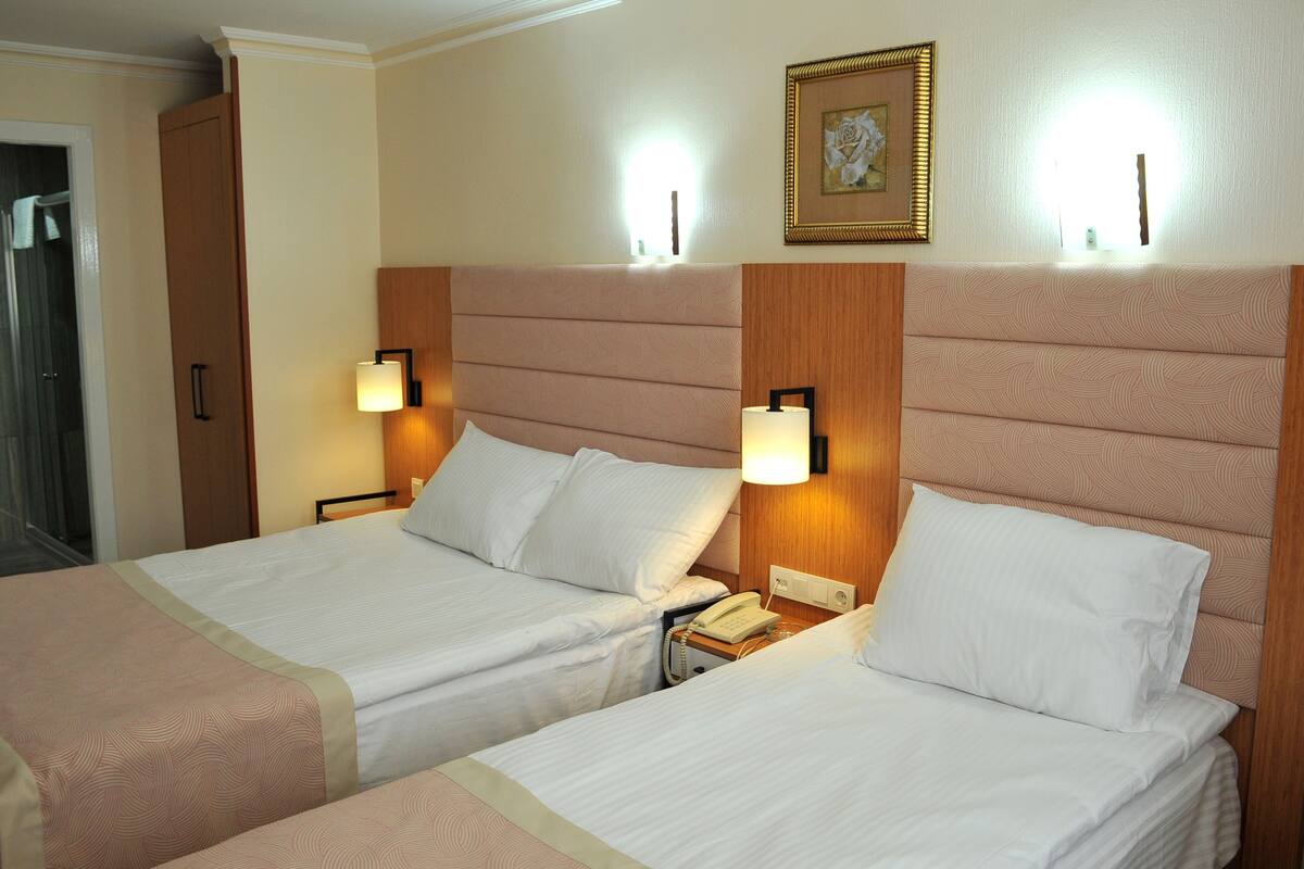 A hotel room with two beds, a wooden headboard, bedside lamps, a telephone, and a framed picture on the wall.