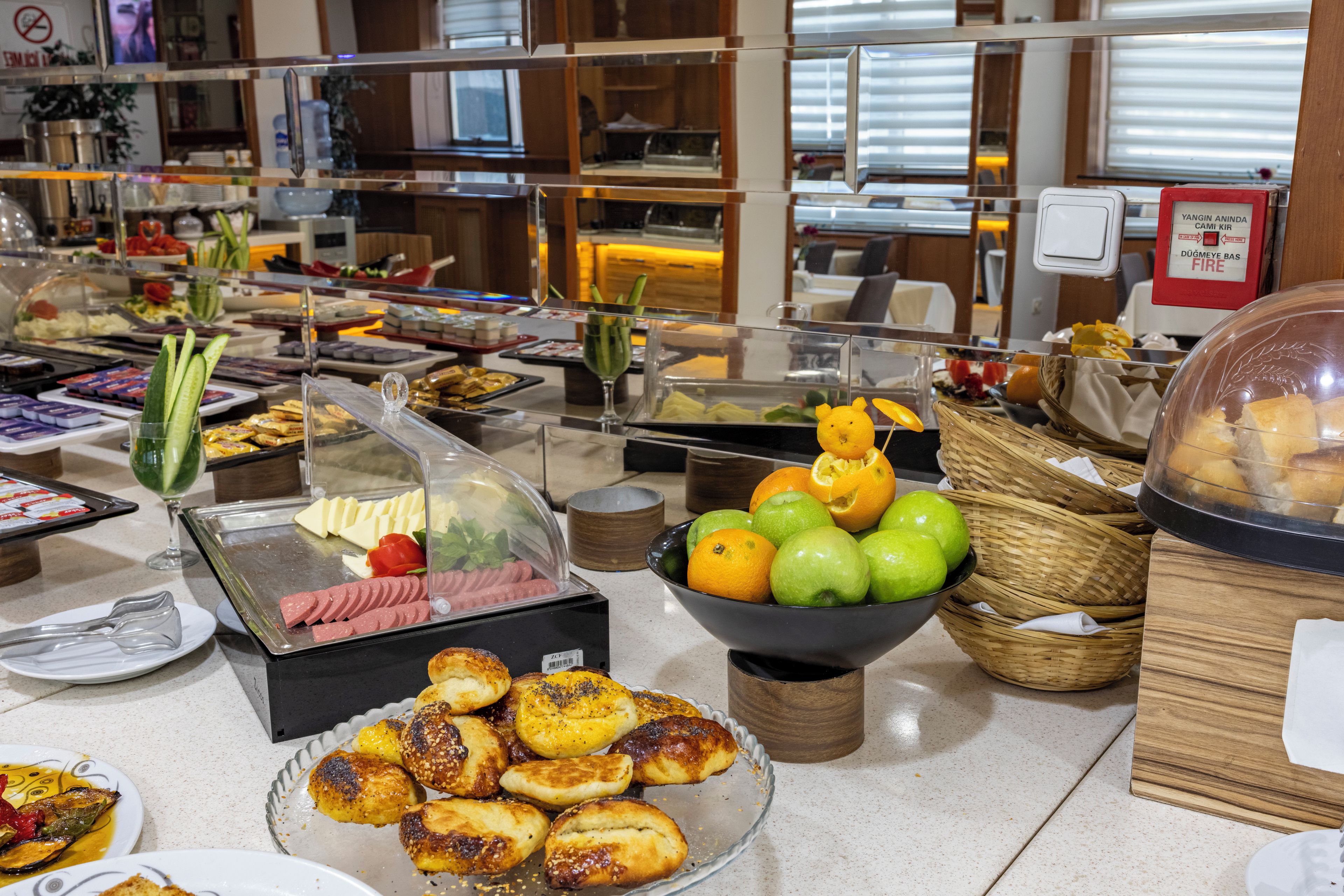 Un bufé con diversas opciones de comida, incluyendo carnes frías, quesos, frutas y pasteles.