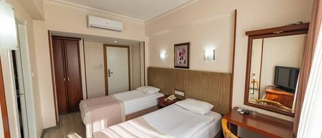 A hotel room with two beds, a desk with a chair, a mirror, and a television.