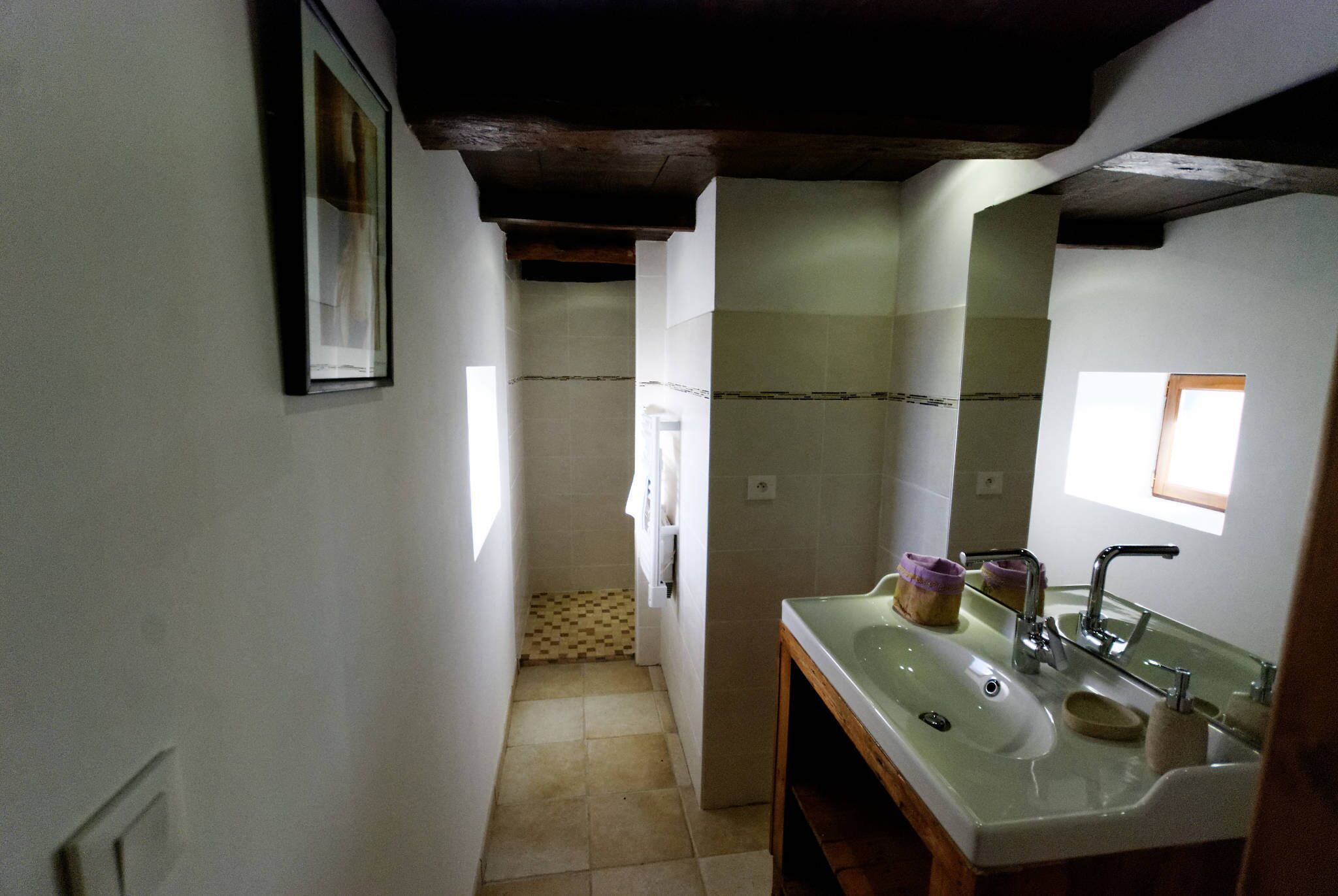 Un baño con lavamanos, espejo y suelo de baldosas.