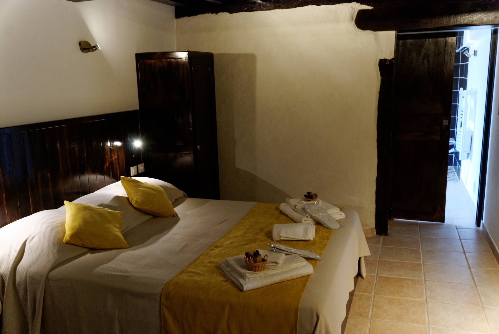 A hotel room with a bed, a wooden wardrobe, and a bathroom door.