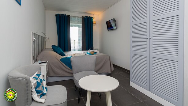 Una habitación pequeña con cama, una mesita, una silla, un televisor y un armario.