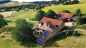 Propiedad rural con una casa grande de techo inclinado, paneles solares y un granero.