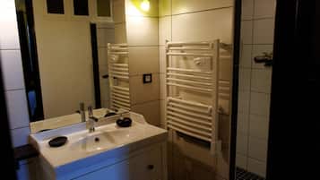 Un baño con lavamanos blanco, espejo y toallero.