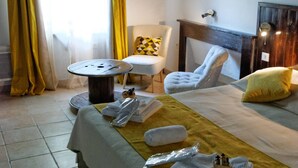 Una habitación de hotel con una cama, una silla, una mesita y una ventana con cortinas.