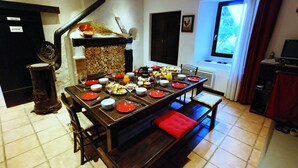 Un comedor con una mesa larga dispuesta para una comida, una chimenea y un ventanal con cortinas.