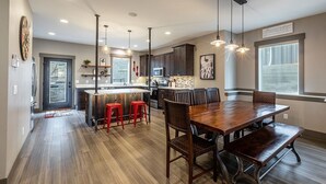 A spacious kitchen with a central island, red bar stools, and pendant lighting.