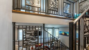 A multi-level interior with a staircase, metal railings, and artwork.