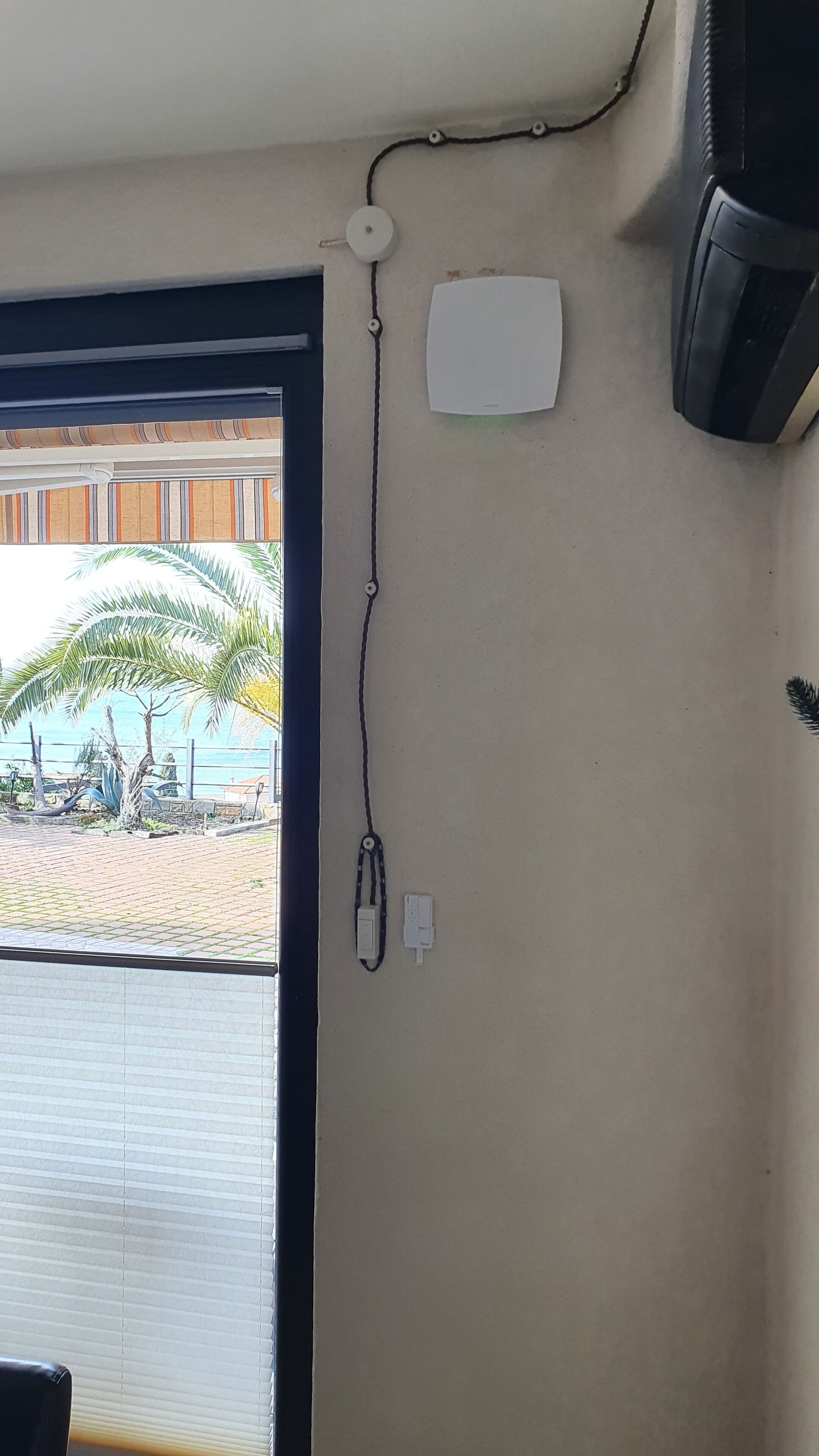 A room with a window, a wall-mounted air conditioner, and a power outlet.