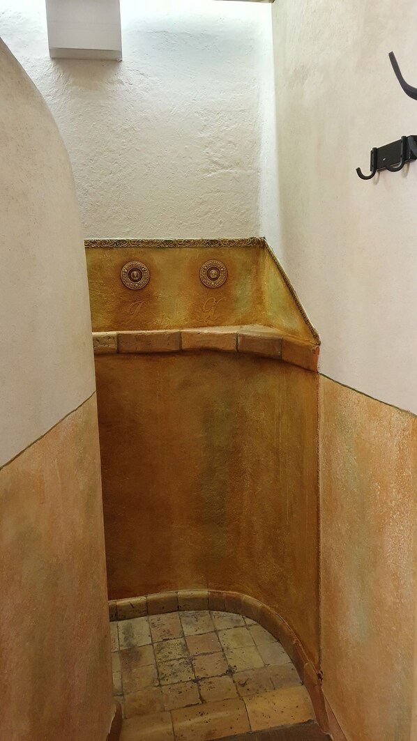 A narrow, enclosed stairwell with a tiled floor and a decorative, rust-colored wall.