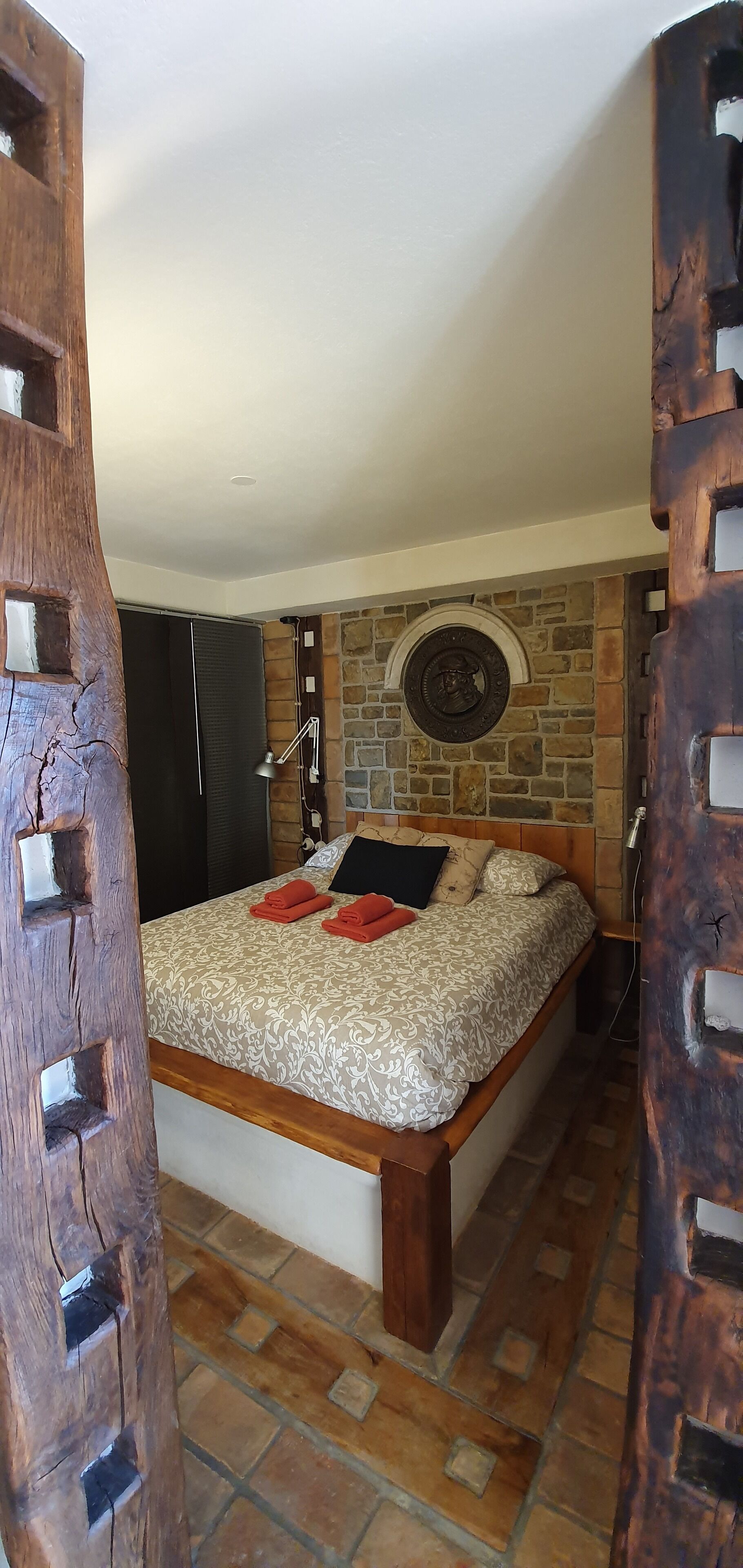 Ein Schlafzimmer mit einem Bett, einer Steinwand und einem Holztürrahmen.