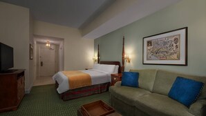 Ett hotellrum med en säng, en soffa, en tv och en inramad karta på väggen.