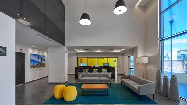 Un hall d’entrée moderne avec un canapé, des fauteuils, une table basse et un comptoir de réception.