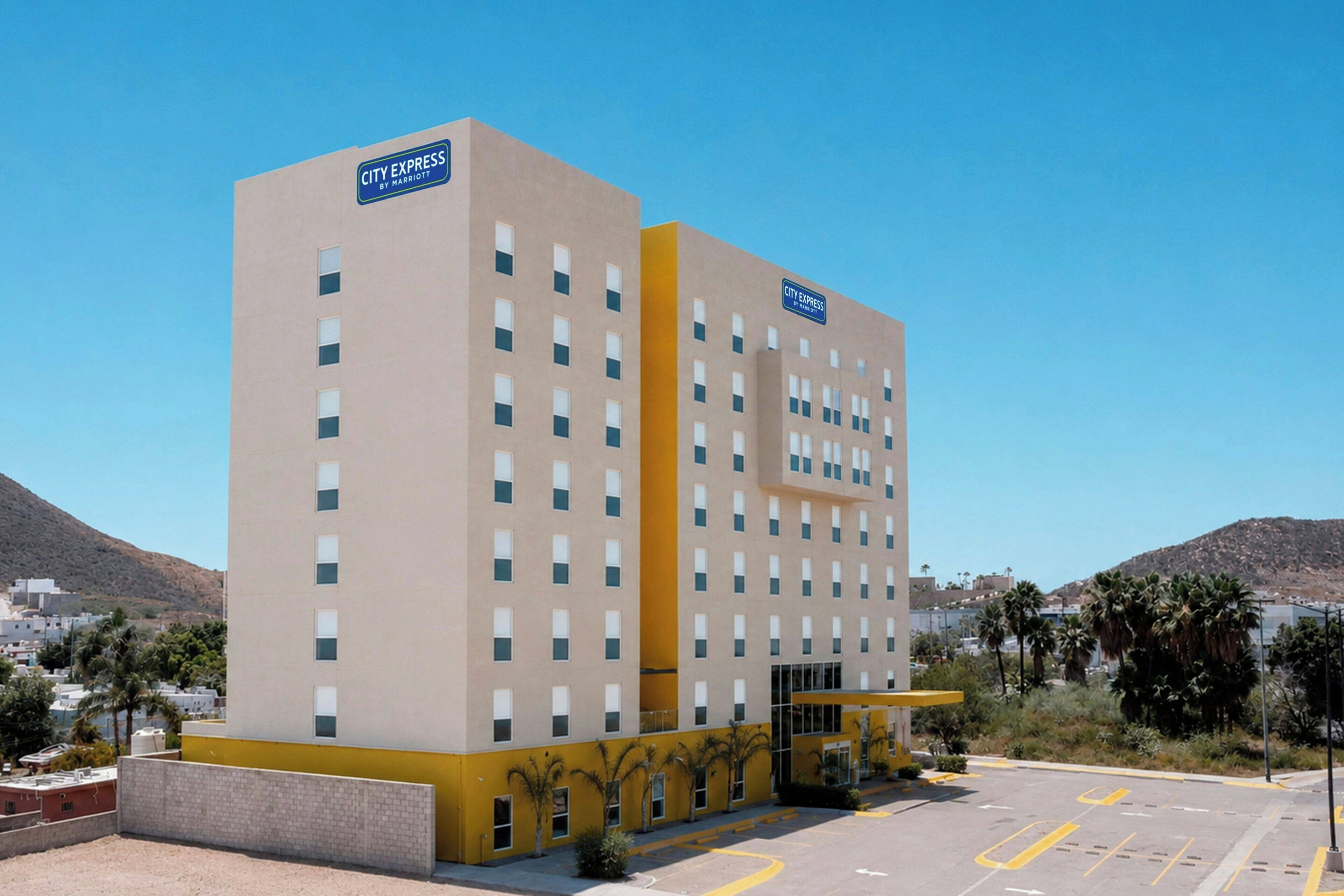 Un hotel a più piani con facciata lineare, un ingresso ben visibile e un'area di parcheggio antistante.