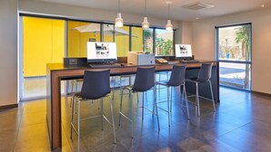 Un espace de bureau moderne comprenant une grande table, quatre chaises et deux écrans d’ordinateur.