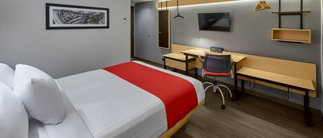 Quarto de hotel com cama, escrivaninha, cadeira, televisão e ar condicionado.