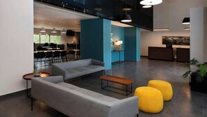 Un hall d’entrée moderne avec un canapé, des poufs, une table basse et un comptoir d’accueil.